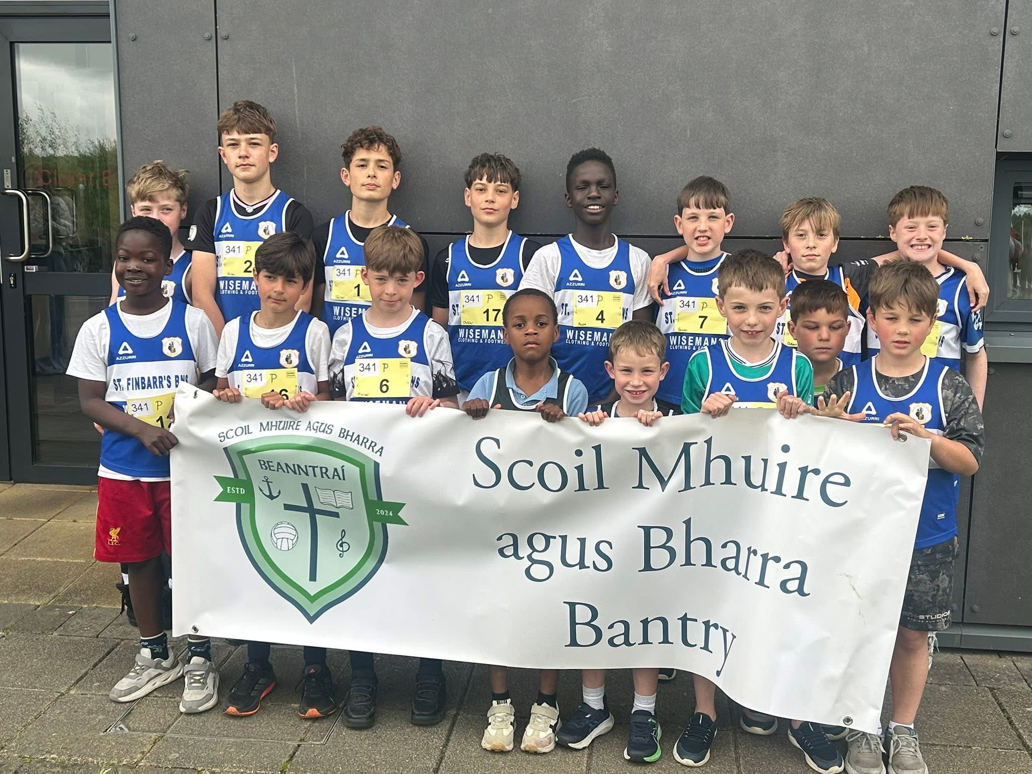 School athletics team wearing race numbers and holding the school banner